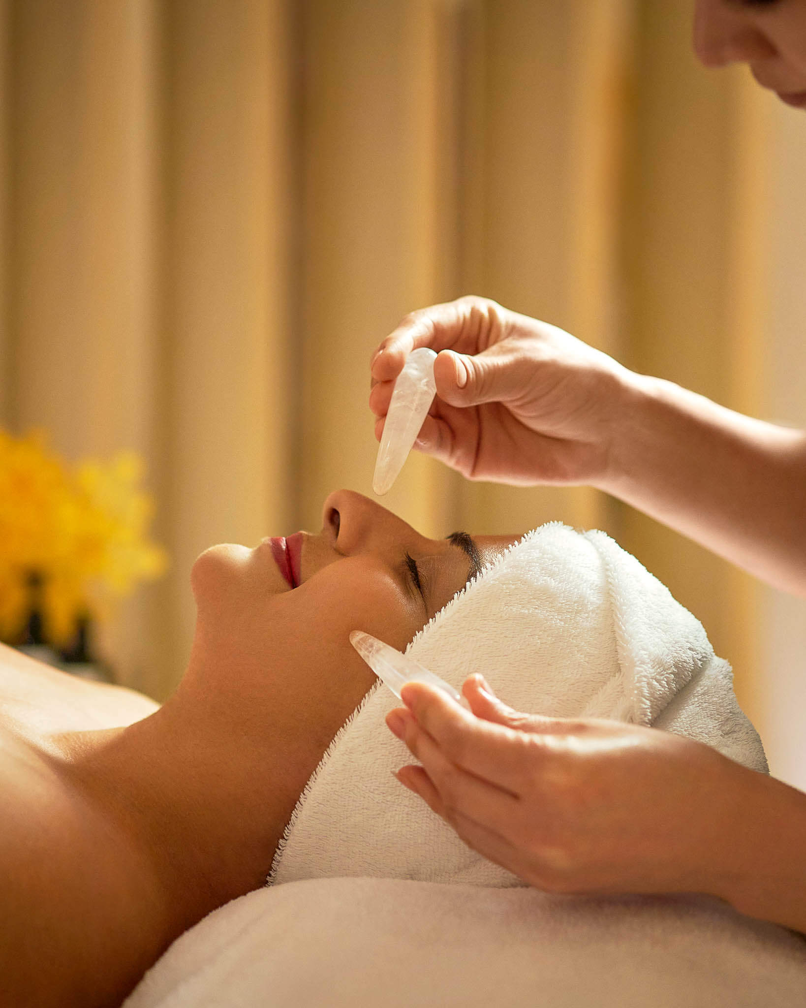 A woman in a spa receives a crystal healing facial.
