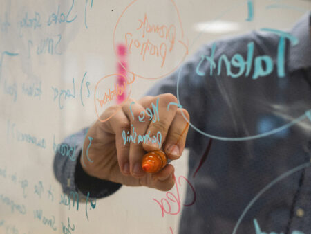 How to become a highly divergent thinker. Image of someone scribbling on transparent board.